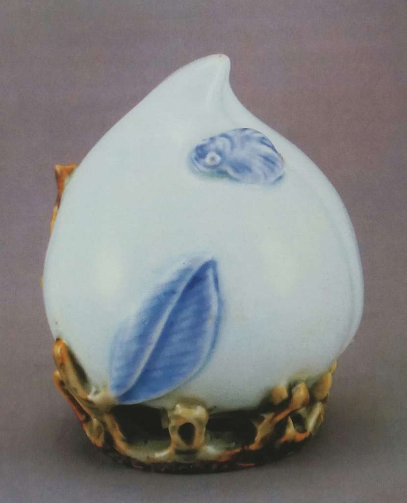 青花白瓷辰砂桃形水滴- A white vase with blue leaves on it