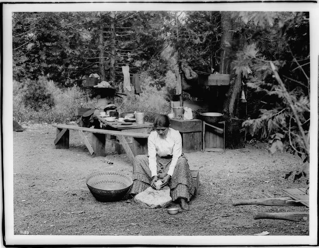 Paiute indian woman sitting on a small wooden crate grinding acorns on ...