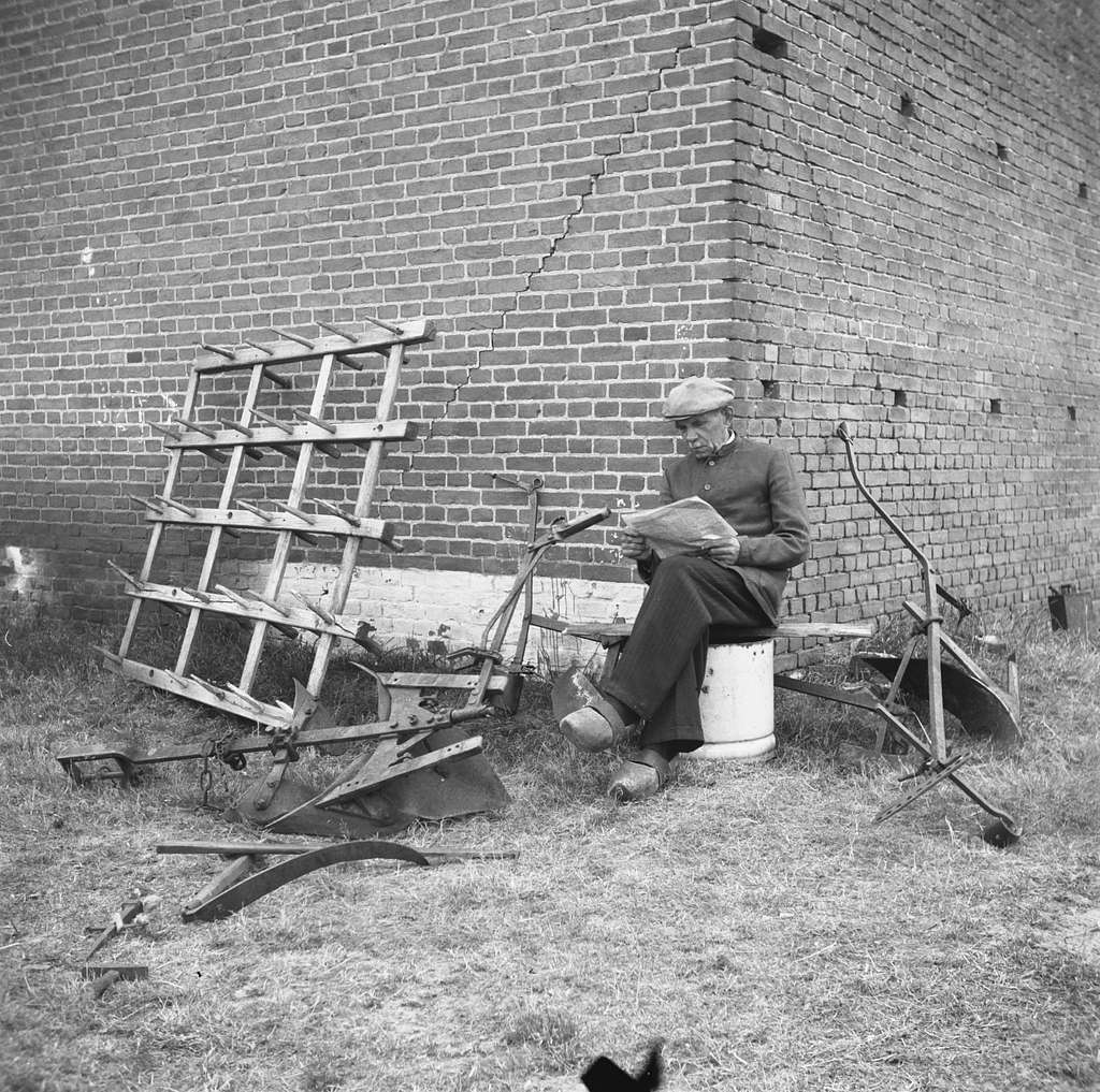 Annexatie Boer leest krant bij een hoek van zijn boerderij, PICRYL