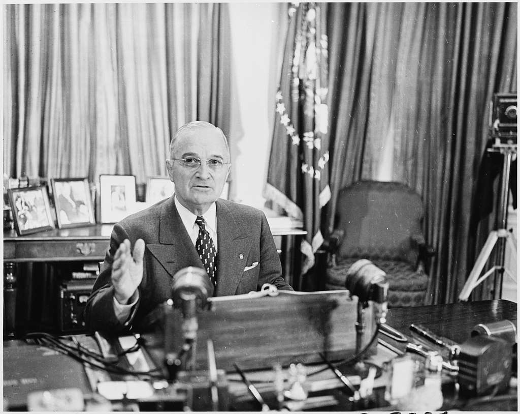 Photograph of President Truman at his desk in the Oval Office, posing ...