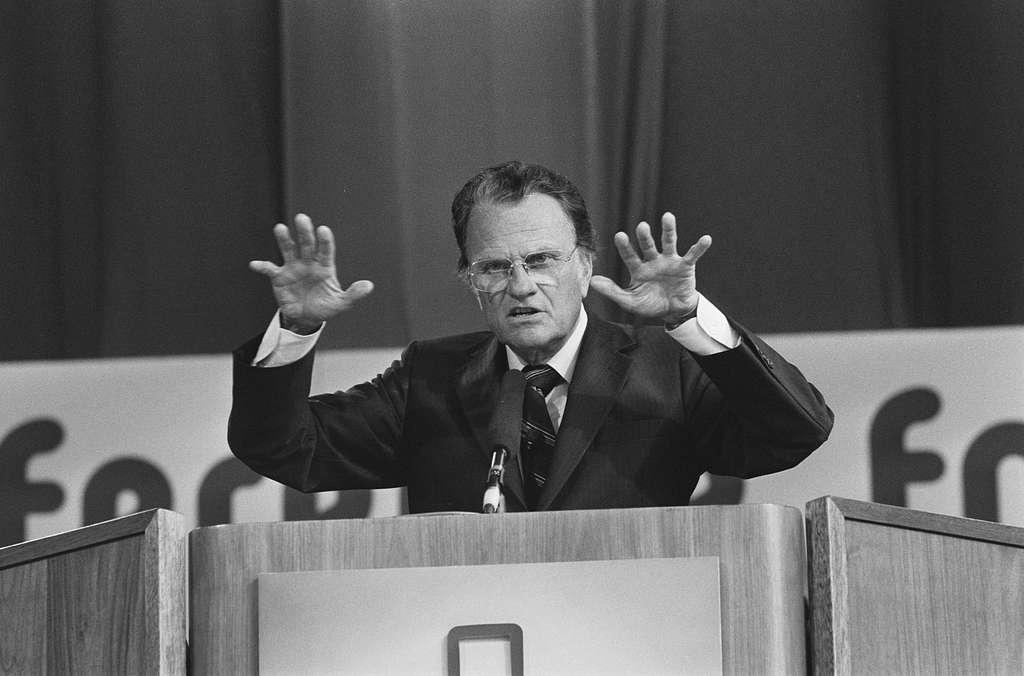 A black and white photo of Billy Graham preaching