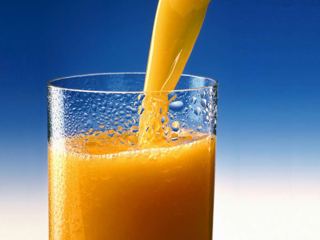 A glass of orange juice on a table in a blue interior. Stock Photo by  puhimec