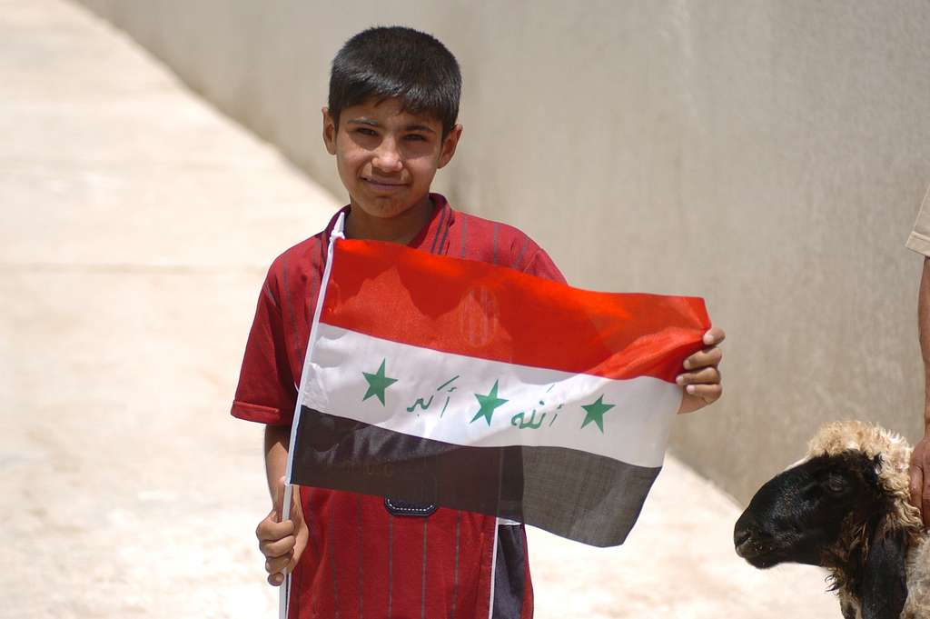 Ein junger Sayafiyah-Junge hält eine irakische Flagge hoch und