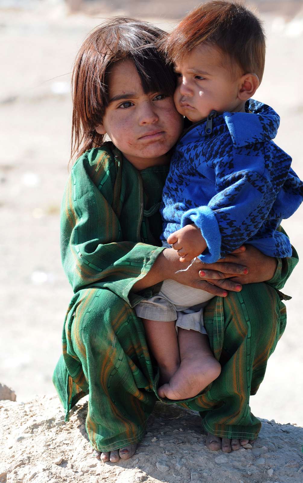 A Kuchi girl holds her little brother as he rests outside - NARA ...