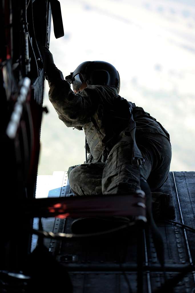 A CH-47 Chinook helicopter crew chief looks out toward - NARA & DVIDS ...