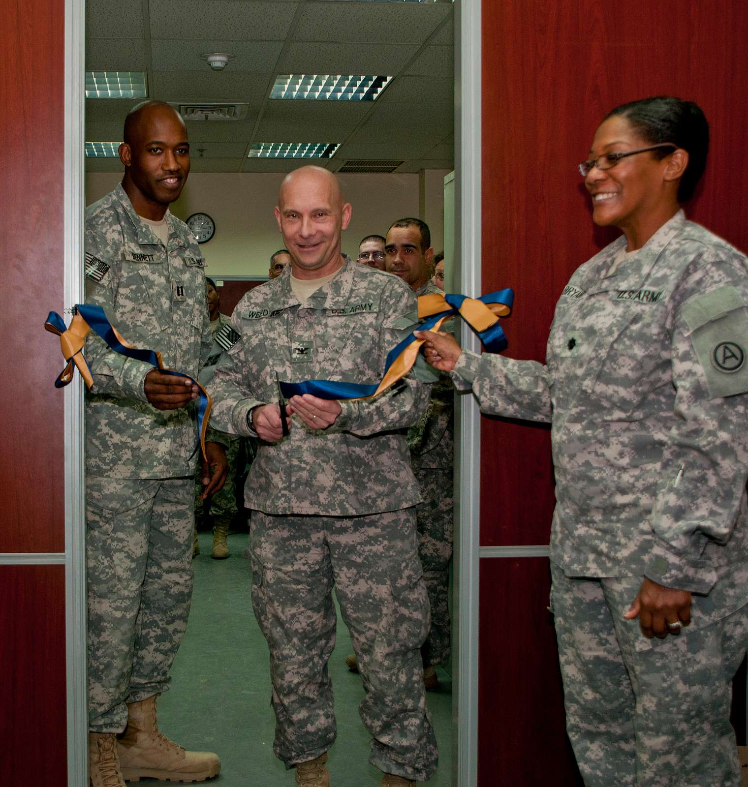 Col. Thomas Brittain, left, cuts the ribbon with a sword with help from  Command Sgt. Major Matthew Barnes, center, and Specialist Stafford Smith  during the Ribbon Cutting Ceremony at the remodel Lewis