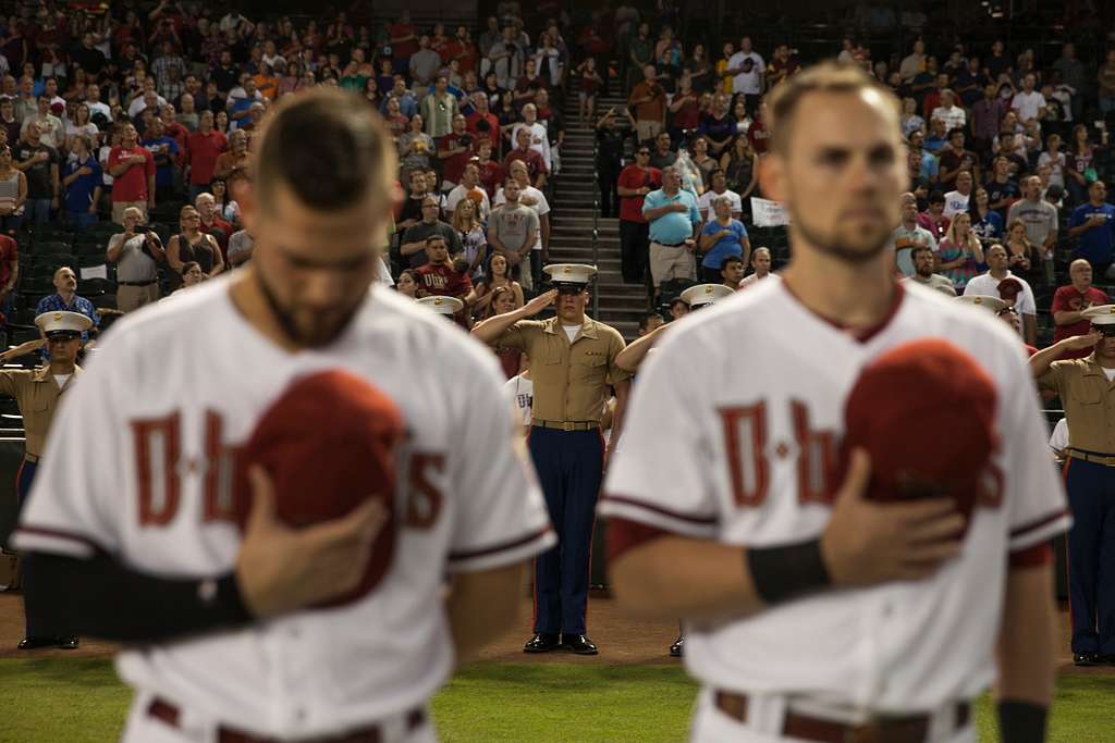 A man salutes during the national anthem before a baseball game