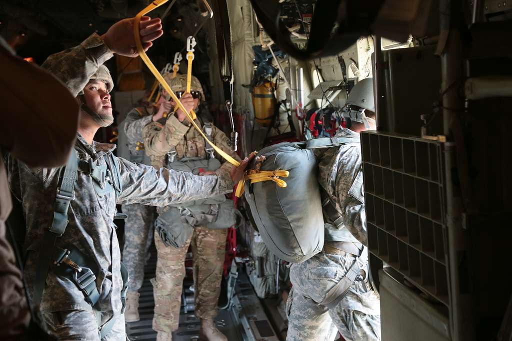U.S. Army paratroopers assigned to Tarantula Team, Operations Group hook up static  lines inside a C-130 aircraft, before conducting airborne operations at the  National Training Center, Fort Irwin, Calif., Oct. 27 2015.