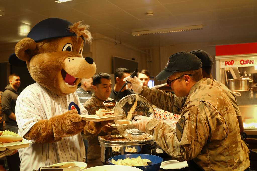 A U.S. Army Soldier's son poses with Clark, the Chicago Cubs mascot, at the  USO at USAG Bavaria in Grafenwoehr, Germany, Dec. 11, 2018. The USO  sponsored a Chicago Cubs mascot tour