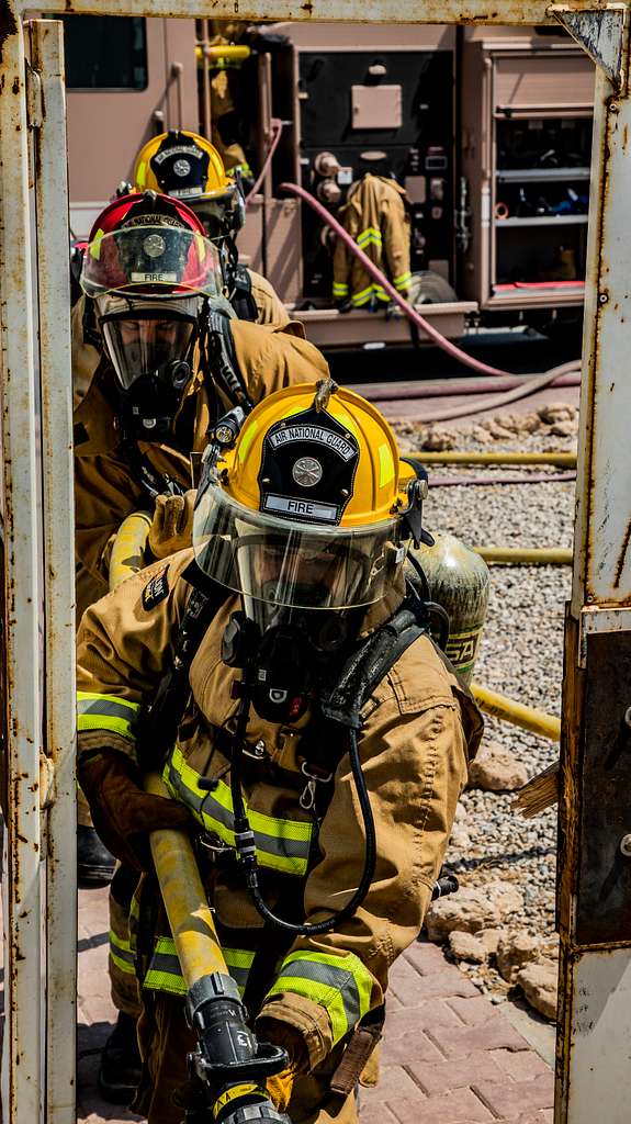 A U.S. Air Force firefighter pulls a fire hose into - PICRYL