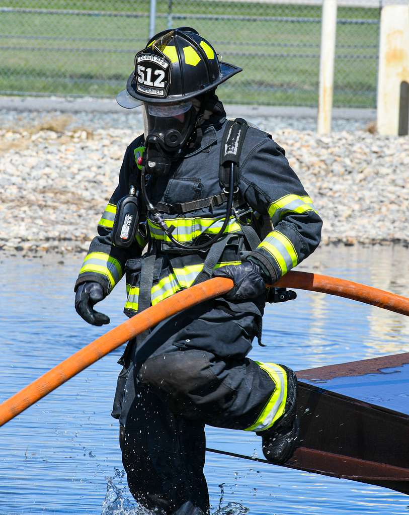 A U.S. Air Force firefighter pulls a fire hose into - PICRYL