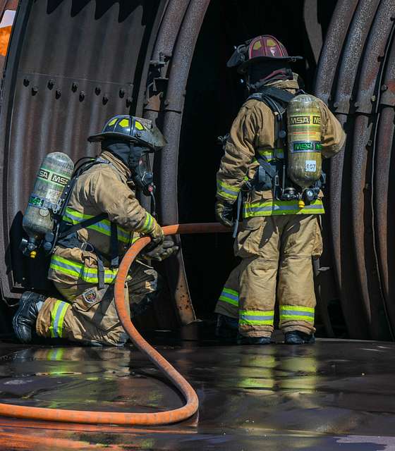 A U.S. Air Force firefighter pulls a fire hose into - PICRYL Public ...