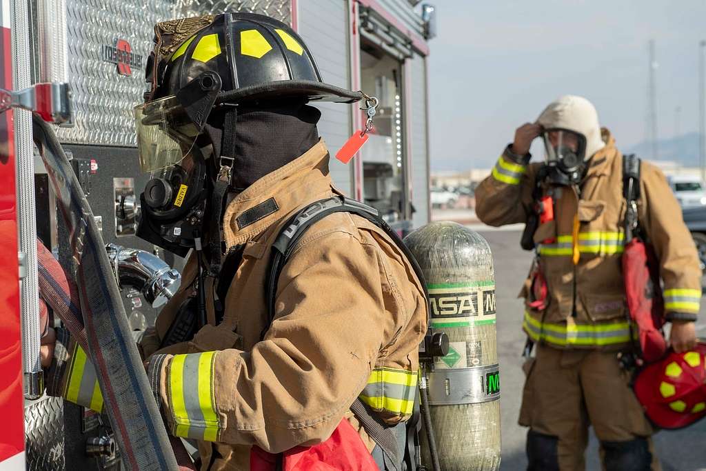 A U.S. Air Force firefighter pulls a fire hose into - PICRYL