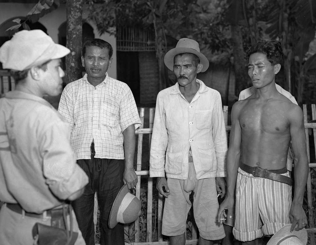 Lokale bevolking. Drie Indonesische mannen in gesprek met een militaire