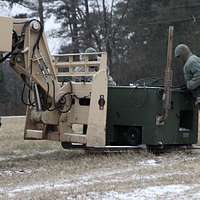 A crane is used to lift a canister containing a MIM-104 Patriot